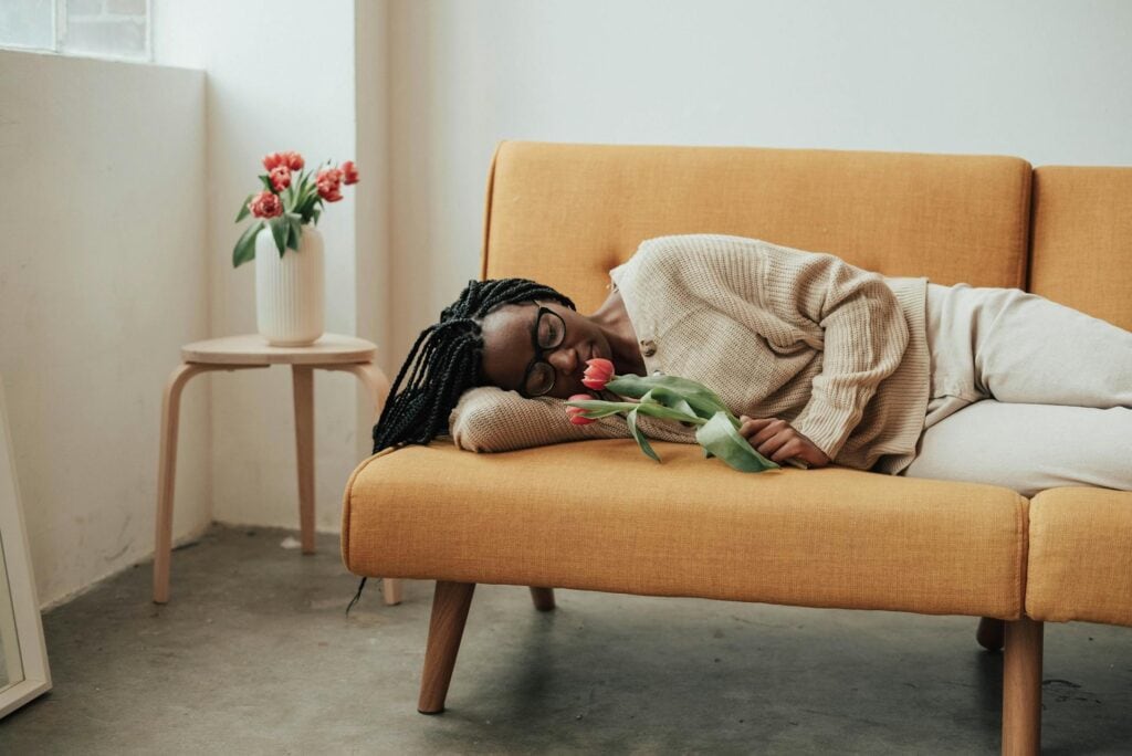 A woman holding a flower and sleeping on a couch