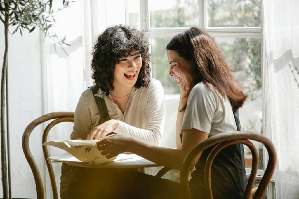 Two women happily chatting over some papers.