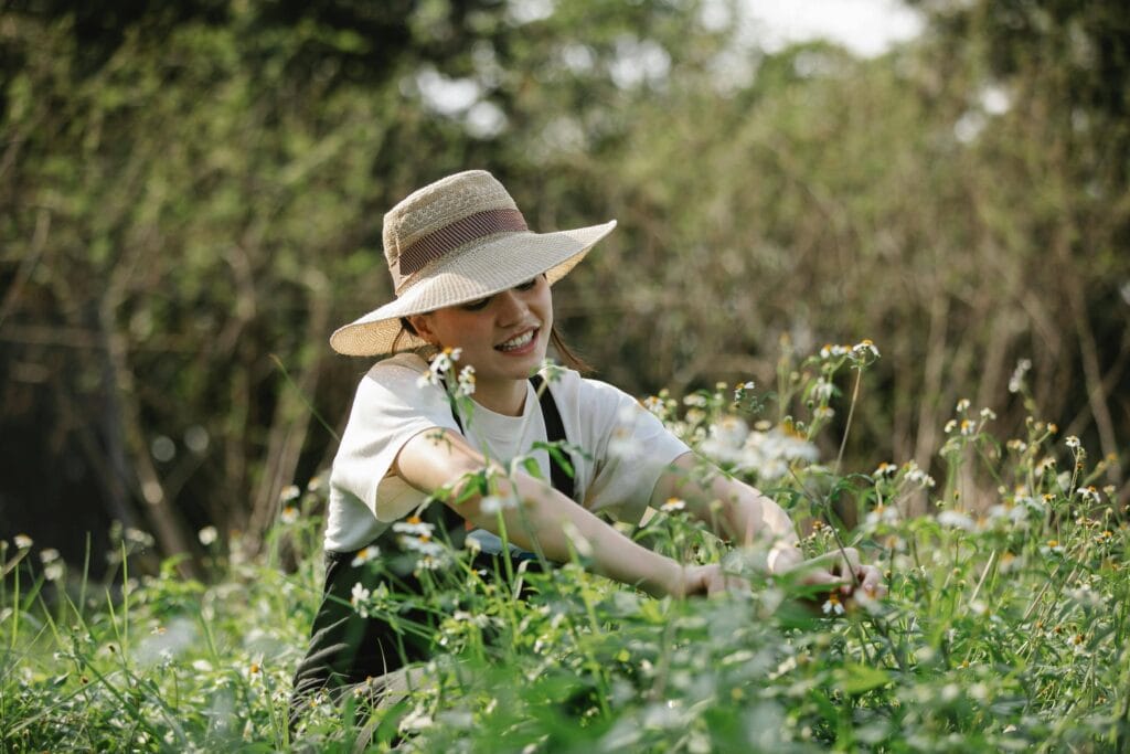 Woman with head sitting in a green field full of flowers - How The Law Of Cause And Effect Can Transform Your Life