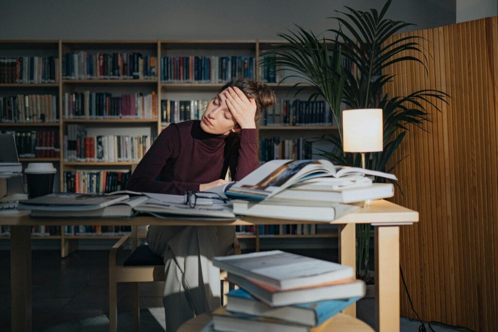 A woman overwhelmed by the books surrounding her.