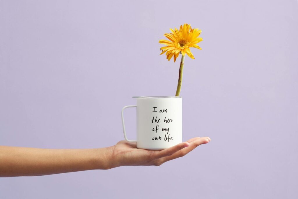 A flower inside a cup with a motivational quote.