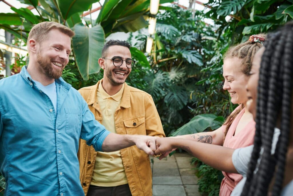 Group of people supporting each other and fist bumping to celebrate success - Signs Your Needs Aren't Being Met & How To Recognize Them