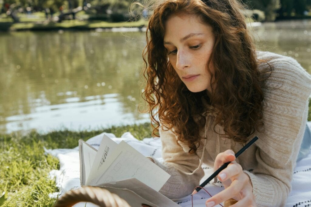 Woman writing in her notes book - 100+ New Month Affirmations To Uplift Your Spirit And Goals