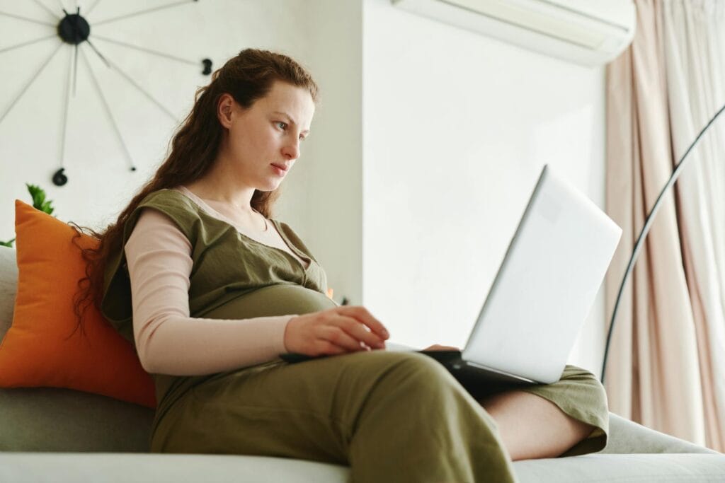 A pregnant woman working from home on her laptop for How To Improve Your Self-Esteem As A Woman: 9 Life-Changing Tips
