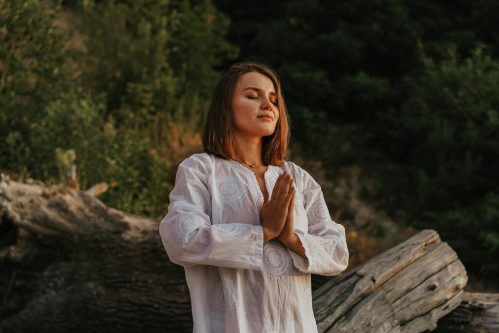 A woman doing a standing meditation in nature.