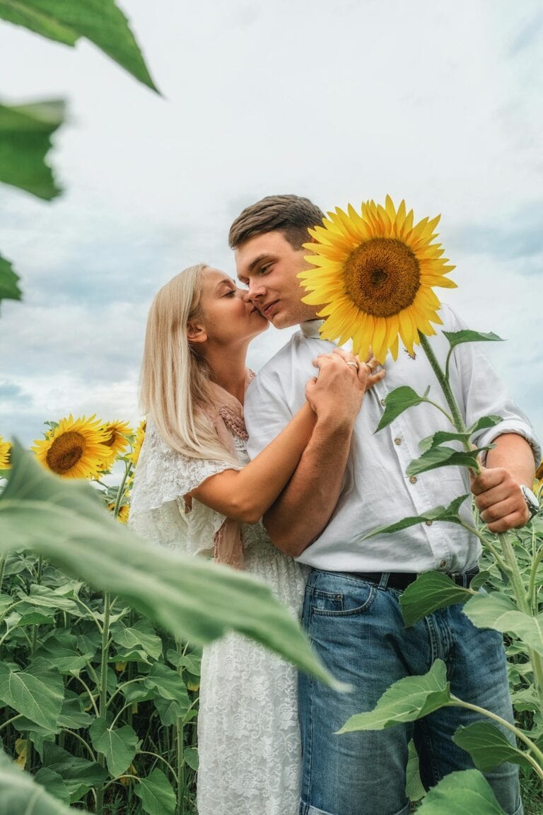 A couple kissing in a field of sunflowers.