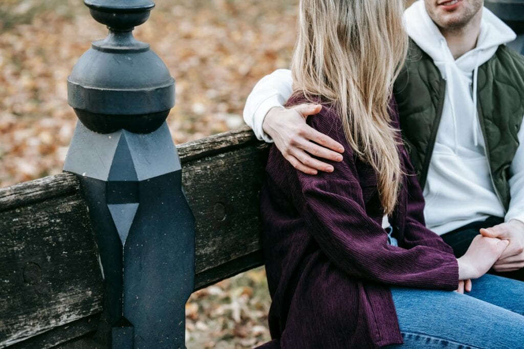 Unhealthy Boundaries In Relationships: Signs And Solutions - in photo: A couple sitting on a bench, discussing.