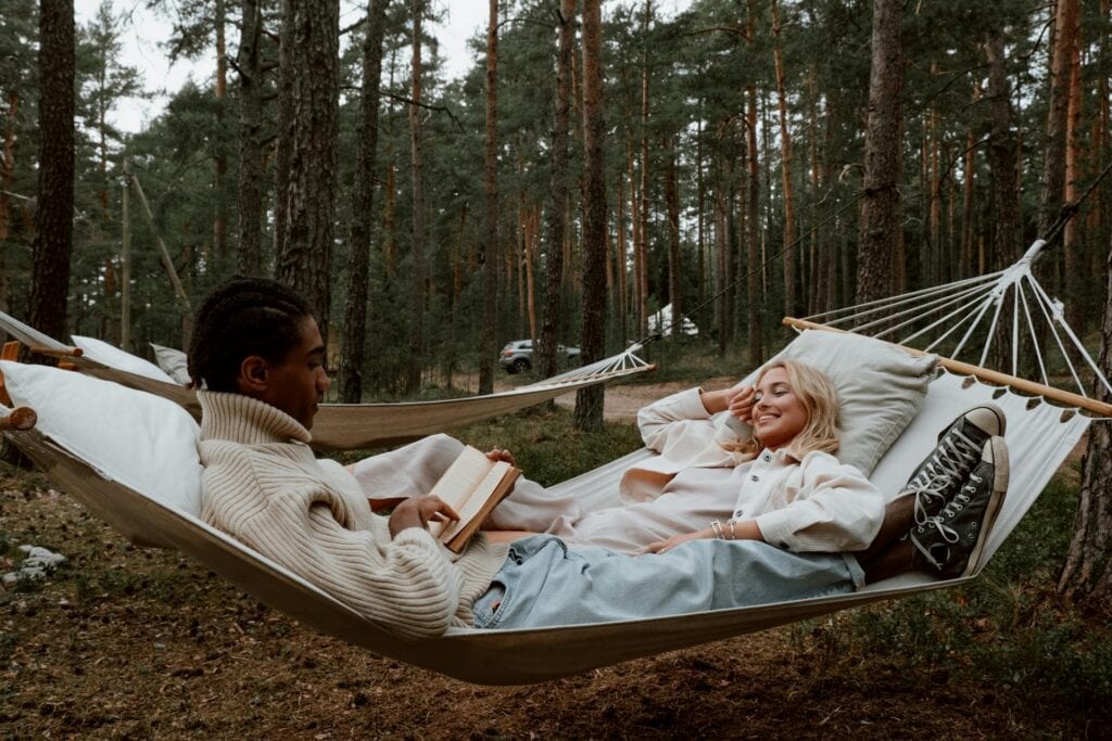 A couple relaxing in a hammock in the forest.