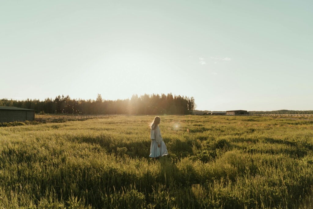 A woman walking in a grass field - 18 Simple Tips On How To Make Your Life More Interesting
