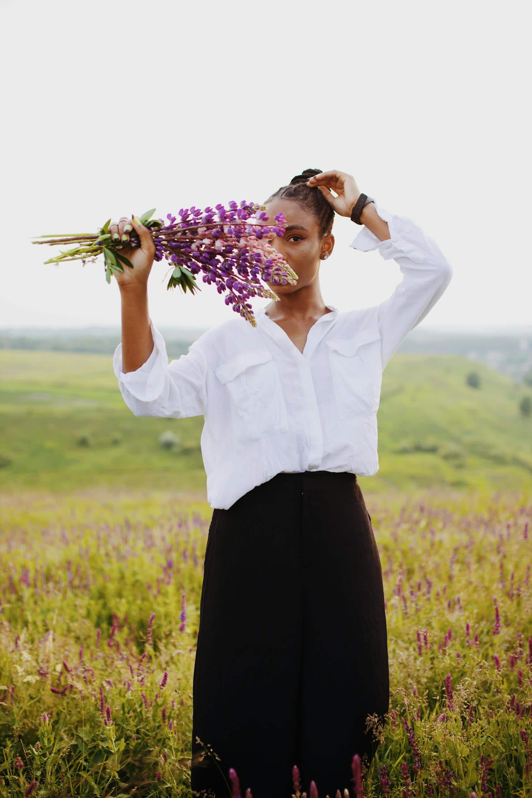 Portrait of a stylish woman holding purple lupines in a vibrant flower field. - How To Be Consistent With A Routine When Life Gets Frantic