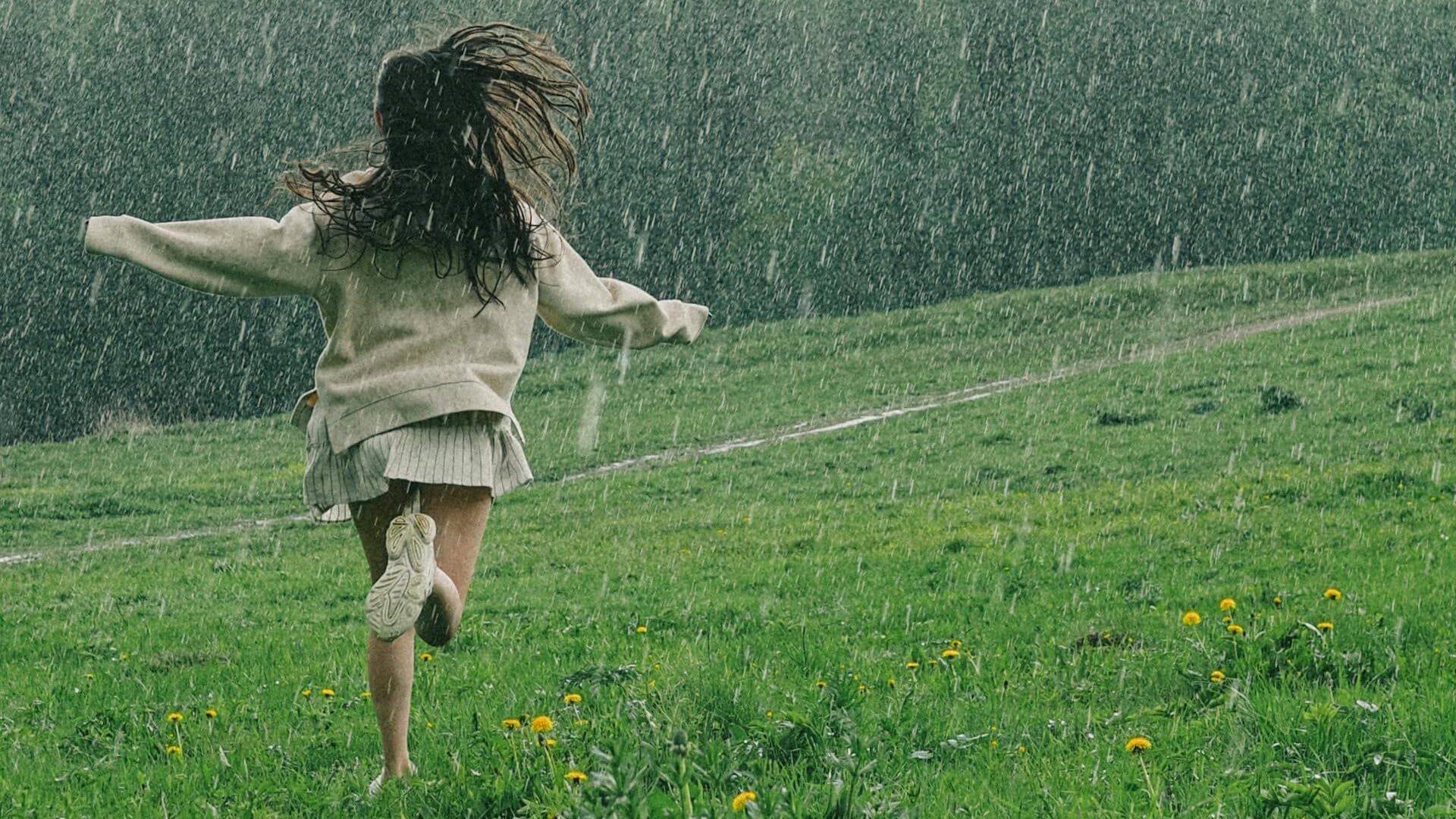 A person runs through a vibrant green field during a serene spring rain shower. - How To Let Go Of Negative Emotions: 10 Helpful Excersises
