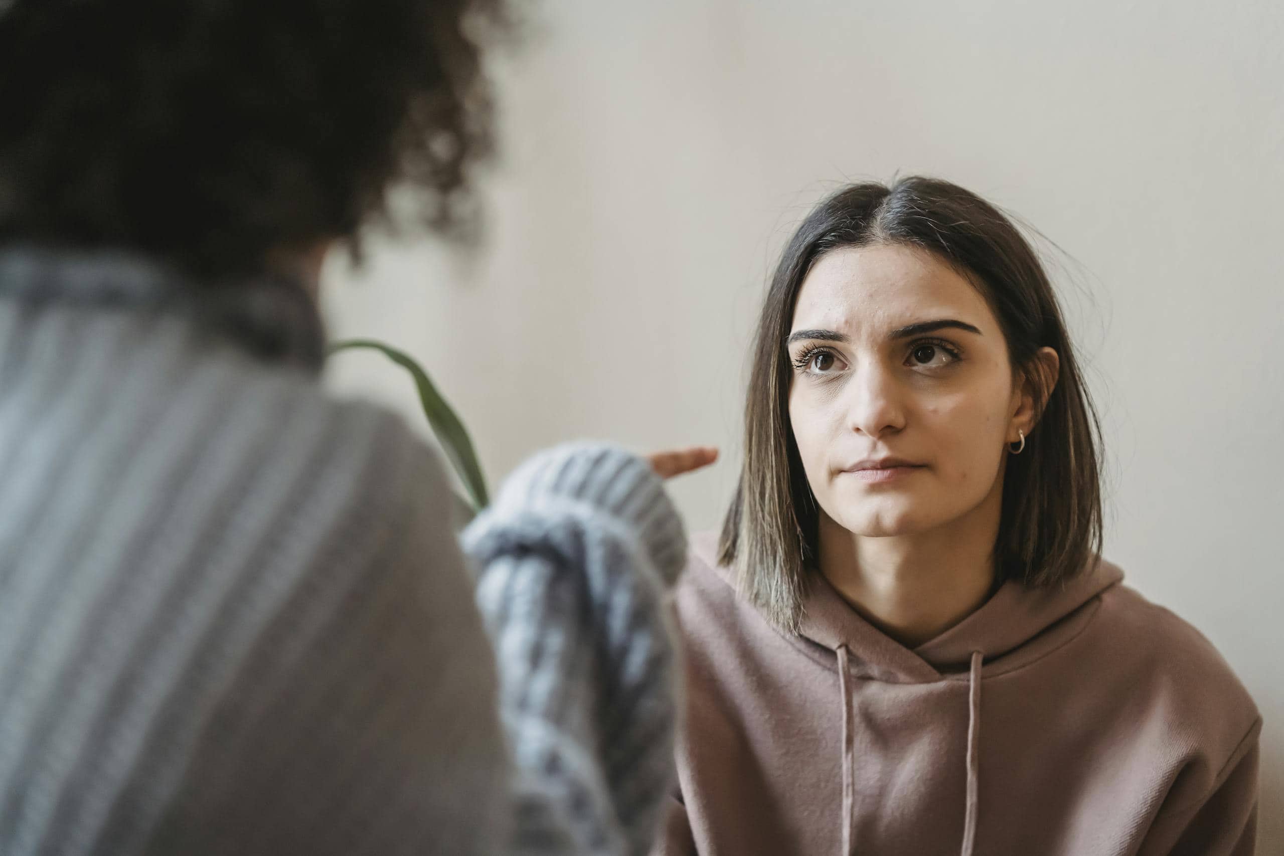 Sad young ladies in casual clothes standing in light apartment near wall while having disagreement and pointing finger in face while looking at each other - How To Avoid Negative People: Surround Yourself With Positivity