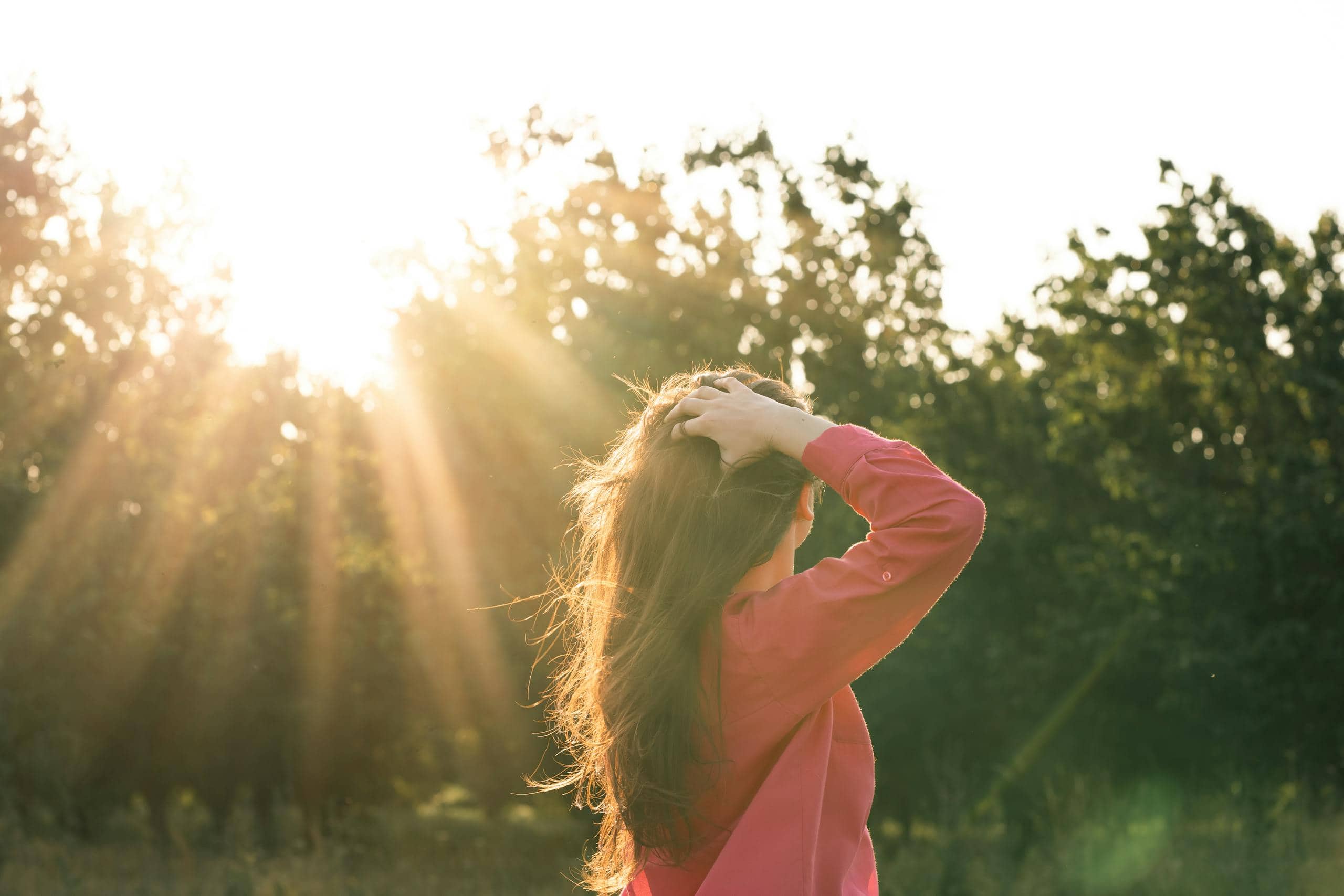 A woman stands in a field bathed in a warm sunset, embracing nature's tranquility. - How To Navigate A Life Transition Without Losing Yourself